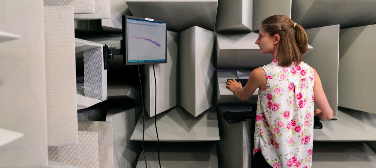 Female noise and vibration engineer collects sound data in an anechoic chamber